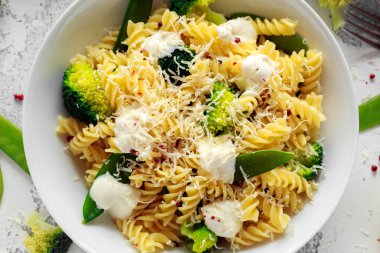 Makarna yeşil sebzeler brokoli, uyuz muhbir ve beyaz tabak içinde krem sos ile