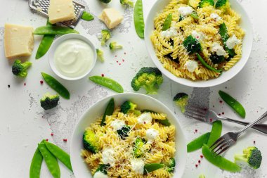 Makarna yeşil sebzeler brokoli, uyuz muhbir ve beyaz tabak içinde krem sos ile