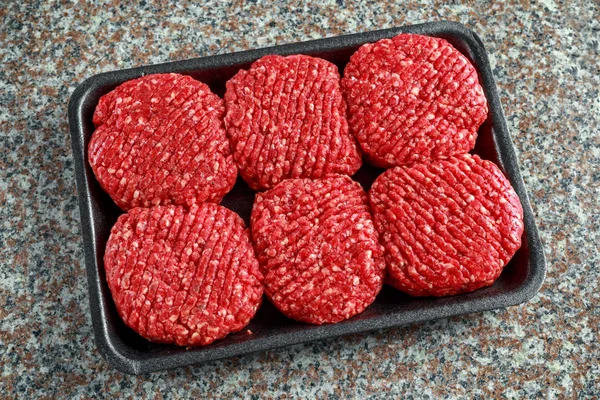 Handmade raw butchers steak burgers on marble chopping board — Stock Photo, Image