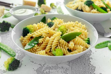 Makarna yeşil sebzeler brokoli, uyuz muhbir ve beyaz tabak içinde krem sos ile