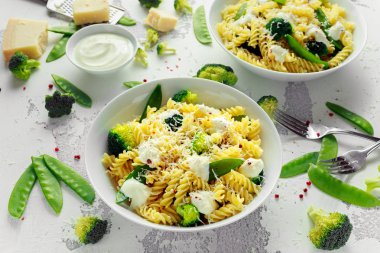 Makarna yeşil sebzeler brokoli, uyuz muhbir ve beyaz tabak içinde krem sos ile