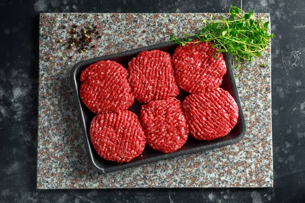 Carniceros crudos hechos a mano carne hamburguesas sobre tabla de cortar de mármol — Foto de Stock