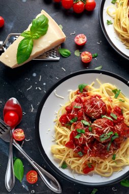 Spagetti makarna köfte domates sosu, fesleğen, koyu arka plan üzerinde otlar parmesan peyniri ile