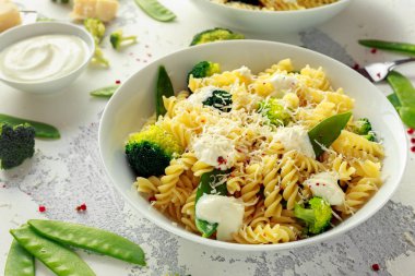 Makarna yeşil sebzeler brokoli, uyuz muhbir ve beyaz tabak içinde krem sos ile