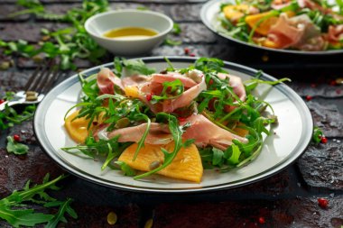 Taze roka, parma jambonu, zeytin yağı, kabak çekirdeği ve otlar ile lezzetli Trabzon hurması salata. Sonbahar, kış sağlıklı gıda