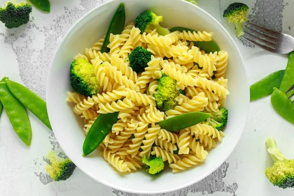 Makarna yeşil sebzeler brokoli, uyuz muhbir ve beyaz tabak içinde krem sos ile