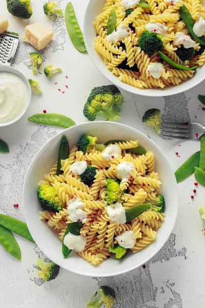 Makarna yeşil sebzeler brokoli, uyuz muhbir ve beyaz tabak içinde krem sos ile