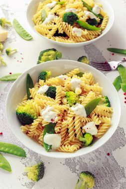 Makarna yeşil sebzeler brokoli, uyuz muhbir ve beyaz tabak içinde krem sos ile