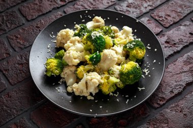 Haşlanmış brokoli, karnabahar salatası parmesan peyniri siyah bir plaka ile. sağlıklı gıda kavramı