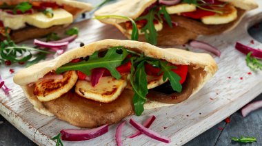 Kırmızı biber ve soğan bir beyaz tahta ile doldurulmuş mantar ve Hellim pittas.