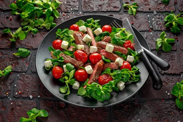 Lédús marha bélszín Steak Saláta sült paradicsom, feta sajt és fekete lemez zöldségek. egészséges táplálkozás — Stock Fotó