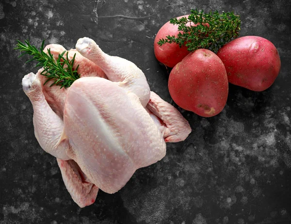 Whole raw Free range chicken in rustic background with rosemary leaf, thyme, red potatoes. ready to cook. — Stock Photo, Image