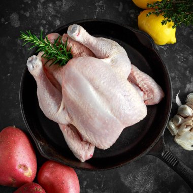 Tüm çiğ ücretsiz aralığı tavuk biberiye yaprağı, kekik, limon, kırmızı patates ve sarımsak ile rustik tavada. pişirmeye hazır