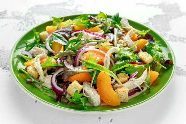 Свіжий салат з курячими грудьми, персиком, червоною цибулею, грінками та овочами в зеленій тарілці. здорова їжа — стокове фото
