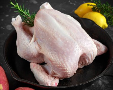 Tüm çiğ ücretsiz aralığı tavuk biberiye yaprağı, kekik, limon, kırmızı patates ve sarımsak ile rustik tavada. pişirmeye hazır