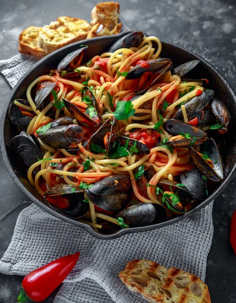 Homemade Pasta Spaghetti with mussels, tomato sauce, chilli and parsley in rustic skillet, pan. sea food meal — Stock Photo, Image