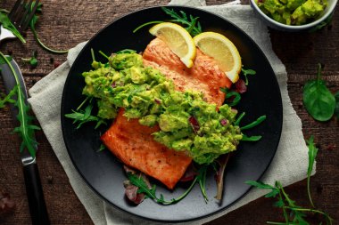 Zeytinyağlı somon steak, fileto avokado salsa ve yeşil siyah plaka üzerinde. ahşap masa. sağlıklı gıda