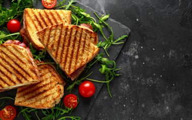 Izgara domuz pastırması, sandviç peynir ve roka ve domates ile taş tabakta servis