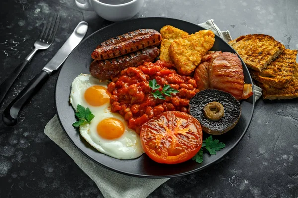 베이컨, 소시지, 계란, 구운된 콩, 감자와 검은 판에 버섯과 전체 영어 아침 식사. 컵 커피. — 스톡 사진