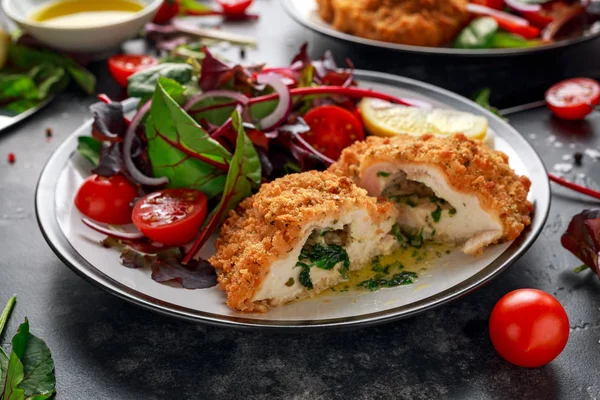 Хлебная курица киевская грудка с маслом, чесноком и травами подается с овощами в тарелке . — стоковое фото