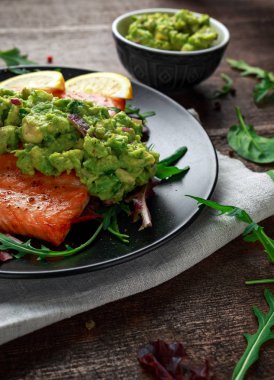 Zeytinyağlı somon steak, fileto avokado salsa ve yeşil siyah plaka üzerinde. ahşap masa. sağlıklı gıda