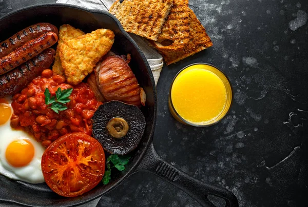 완전 한 영어 아침 식사 베이컨, 소시지, 계란, 구운된 콩, 감자와 버섯 소박한 프라이팬, 팬. 오렌지 주스 — 스톡 사진