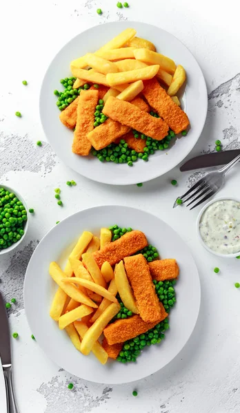 British Traditional Fish finger and chips with peas and tartar sauce in a white plate.