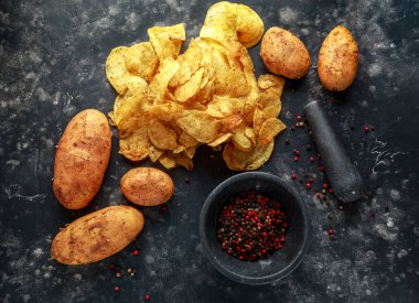 Kaymaklı biber patates cipsi, pişmiş cips taş tahta üzerinde deniz tuzu ile mermer havaneli ve harç ile snack.