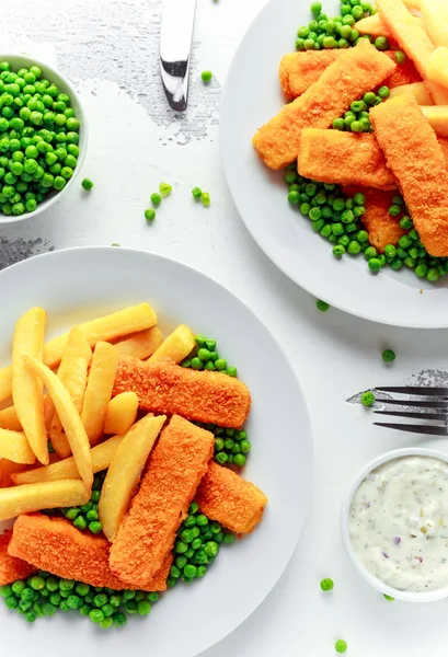 Brittiska traditionella Fiskpinnar och chips med ärtor och tartarsås i en vit platta. — Stockfoto