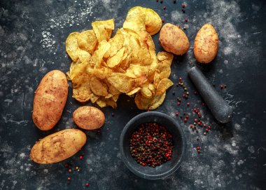 Kaymaklı biber patates cipsi, pişmiş cips taş tahta üzerinde deniz tuzu ile mermer havaneli ve harç ile snack.