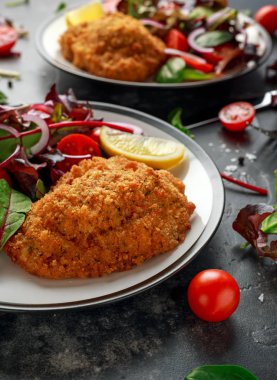 Ekmekli Tavuk Kiev meme tereyağı, sarımsak ve otlar ile doldurulmuş bir tabakta sebze ile servis.