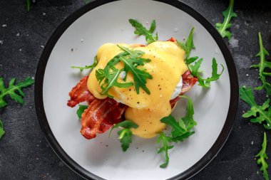 Yumurta Benedict üzerinde İngilizce muffin gevrek domuz pastırması, vahşi roket salata ve hollandaise sosu ile.