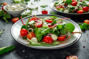Taze kiraz domates, Mozzarella salatası yeşil salata karışımı ve kırmızı soğan ile. tabakta. sağlıklı gıda.