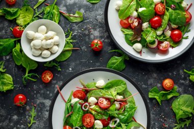 Taze kiraz domates, Mozzarella salatası yeşil salata karışımı ve kırmızı soğan ile. tabakta. sağlıklı gıda.