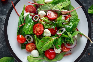 Taze kiraz domates, Mozzarella salatası yeşil salata karışımı ve kırmızı soğan ile. tabakta. sağlıklı gıda.