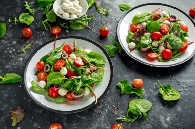 Taze kiraz domates, Mozzarella salatası yeşil salata karışımı ve kırmızı soğan ile. tabakta. sağlıklı gıda.