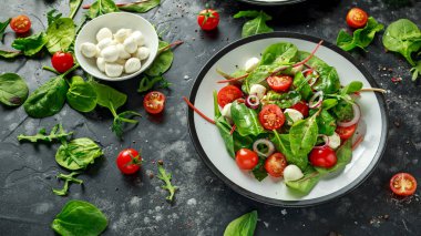Taze kiraz domates, Mozzarella salatası yeşil salata karışımı ve kırmızı soğan ile. tabakta. sağlıklı gıda.