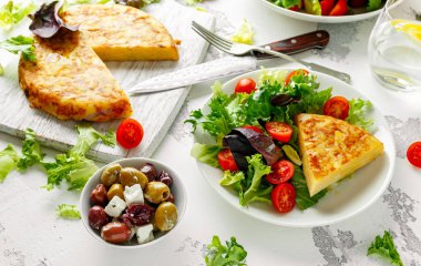 İspanyol tortilla, omlet patates, soğan, sebze, domates, zeytin ve beyaz bir tabak içinde otlar ile. Kahvaltı, sağlıklı gıda.