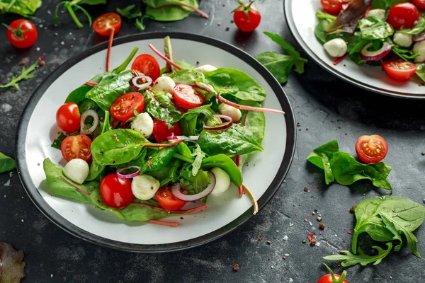 Taze kiraz domates, Mozzarella salatası yeşil salata karışımı ve kırmızı soğan ile. tabakta. sağlıklı gıda.