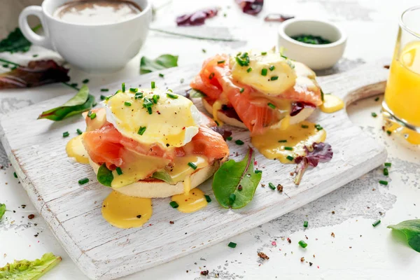 Yumurta Benedict İngiliz çöreği somon füme, marul salata karışımı ve hollandaise soslu beyaz tahta üzerinde üzerinde — Stok fotoğraf