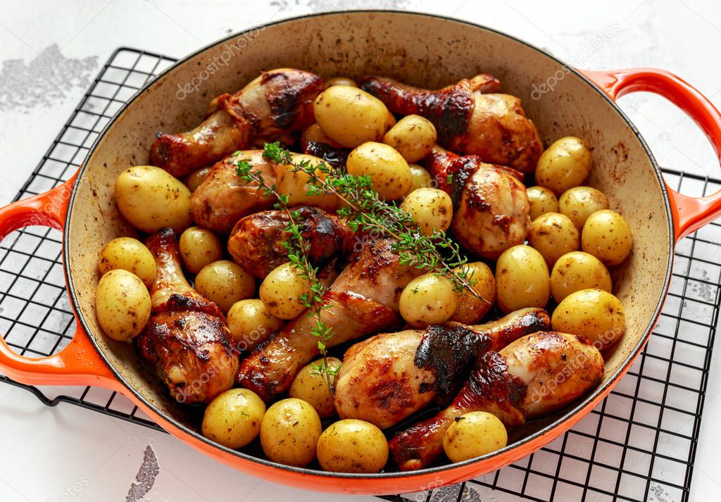 Oven baked Chicken drumsticks and new baby potatoes with thyme in pan, ready to serve