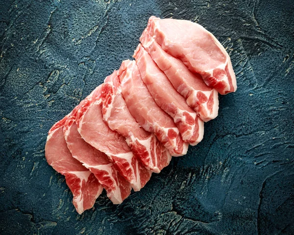 Raw Pork Loin chops on blue background