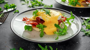 Yumurta Benedict üzerinde İngilizce muffin gevrek domuz pastırması, vahşi roket salata ve hollandaise sosu ile.