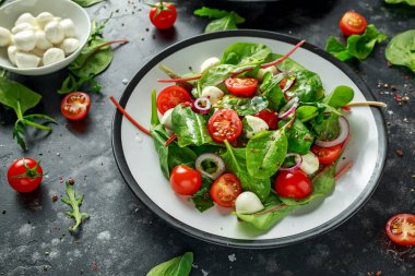 Taze kiraz domates, Mozzarella salatası yeşil salata karışımı ve kırmızı soğan ile. tabakta. sağlıklı gıda.