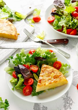 İspanyol tortilla, omlet patates, soğan, sebze, domates, zeytin ve beyaz bir tabak içinde otlar ile. Kahvaltı, sağlıklı gıda.