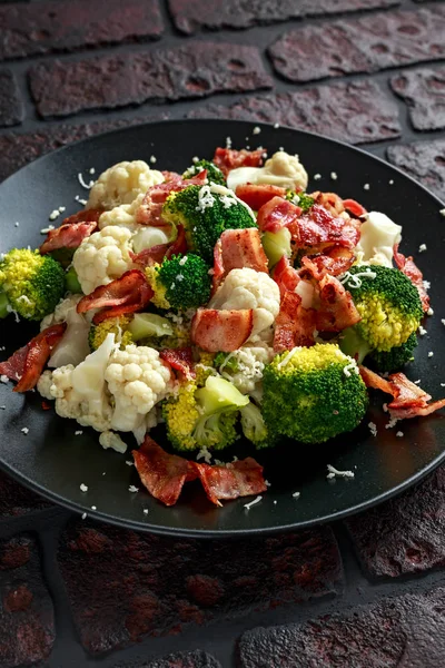 Steamed Broccoli, Cauliflower Salad with Bacon, parmesan cheese in a black plate. healthy food concept