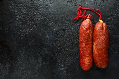 traditional Balearic raw cured meat sobrassada sausage made from ground pork, paprika and spices on rustic black background clipart