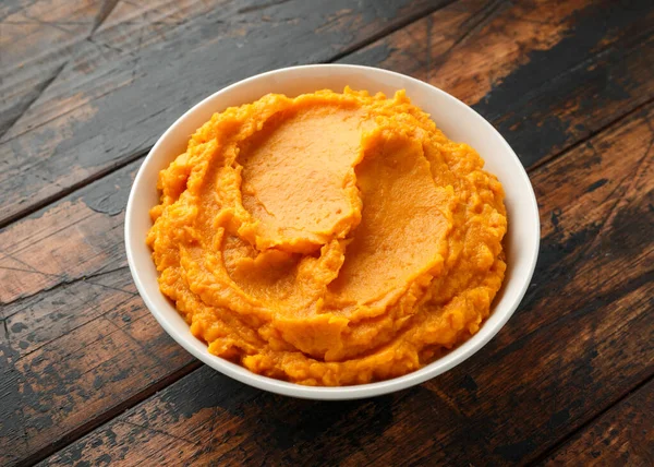 Purée de patates douces dans un bol blanc sur une table rustique en bois. Aliments sains — Photo