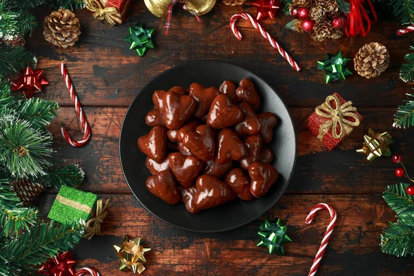 Pan de jengibre de Navidad, corazón de lebkuchen con decoración, regalos, rama de árbol verde en la mesa rústica de madera —  Fotos de Stock