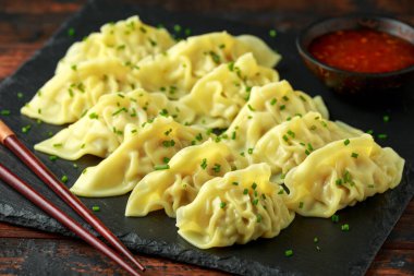 Buharda pişirilmiş yaki Gyoza, acı biber sosu ve susam tohumlarıyla servis edilir.